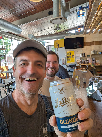 Sam and a family member laughing over nonalcoholic beers at a taproom.